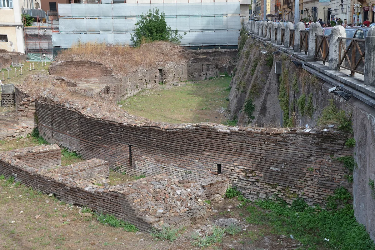 The ruins of the Ludus Magnus beside the Colosseum, an oval of brick walls and curved seating around a sunken arena